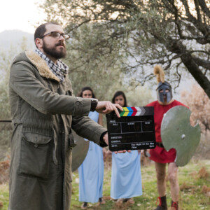 Il regista batte il ciak durante la scena della caduta di Troia per il docufilm "Vennari Santu". Comparse vestite in abiti dell'antica Grecia